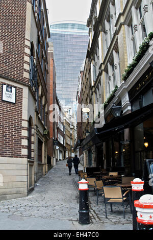 Ein paar gehen hinunter eine alte Gasse, Lovat Lane London EC 3 mit einem neuen Wolkenkratzer in der Ferne. Stockfoto