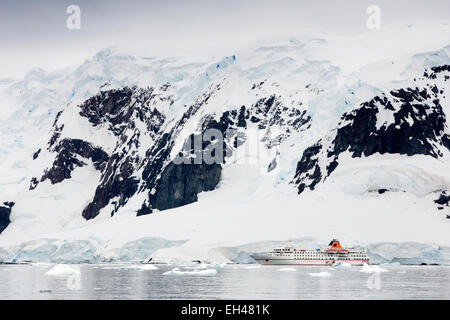 Antarktis, Paradise Bay, MS Hanseatic Kreuzfahrtschiff vor Anker unter schneebedeckten Gipfeln Stockfoto