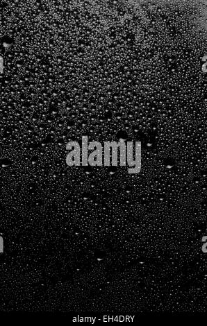 Gruppe von Tropfen mit verschiedenen Dimensionen auf einer Oberfläche in schwarz und weiß als Hintergrund Stockfoto