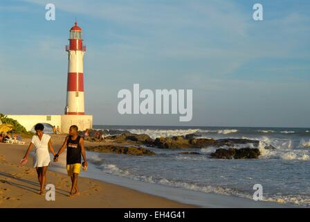 Brasilien, Bahia state, Itapua, Itapua Leuchtturm und am Strand bei Sonnenuntergang, paar Hand in Hand am Strand Stockfoto