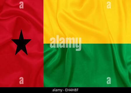 Guinea-Bissau - winken Nationalflagge auf Seide Textur Stockfoto