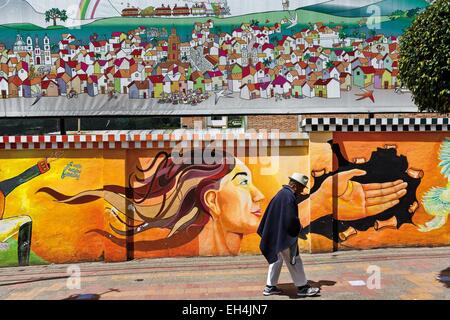 Ecuador, Imbabura, Otavalo, Alter Mann auf einem Bürgersteig vor Graffitiwand vorbei Stockfoto