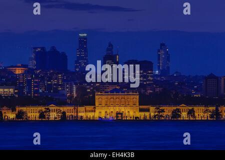 Türkei, Istanbul, Besiktas Bezirk, Dolmabahce Palast (Dolmabahce Sarayi), Nachtansicht von einem beleuchteten Palast vor einem modernen städtischen Bereich am Meer Stockfoto