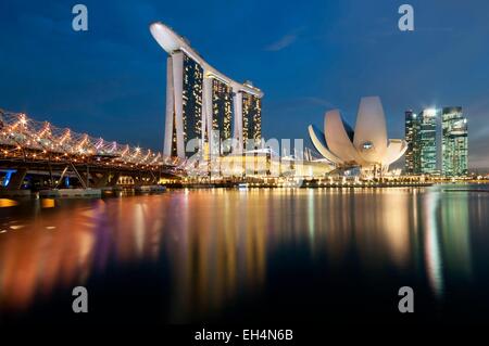 Singapur, Marina Bay, Marina Bay Sands Hotel am Abend mit dem ArtScience Museum, entworfen von dem Architekten Moshe Safdie, die Helix-Brücke auf der linken Seite Stockfoto