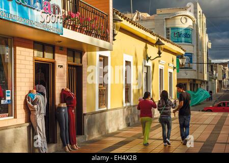 Ecuador, Imbabura, Atuntaqui, Straßenszene von Passanten vor einem Bekleidungsgeschäft auf stürmischen Himmel bei Sonnenuntergang Stockfoto