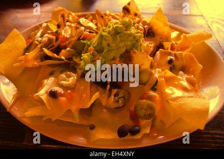 Macho Nachos-ein Hügel aus Mais-Tortilla chips über gebratenen Bohnen, Käse mischen, eingelegte Jalopenos, etc. Stockfoto