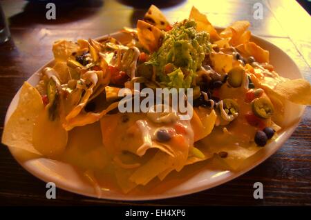 Macho Nachos-ein Hügel aus Mais-Tortilla chips über gebratenen Bohnen, Käse mischen, eingelegte Jalopenos, etc. Stockfoto