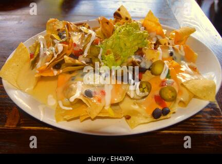 Macho Nachos-ein Hügel aus Mais-Tortilla chips über gebratenen Bohnen, Käse mischen, eingelegte Jalopenos, etc. Stockfoto