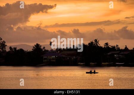 Malaysia, Borneo, Sarawak, Kuching, Silhouette der Fischer auf einem Boot am Sungai Sarawak River bei Sonnenuntergang Stockfoto