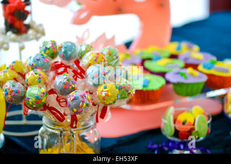 Bunte Lutscher, platziert in einem Glas auf einem Tisch voller Süßigkeiten Stockfoto