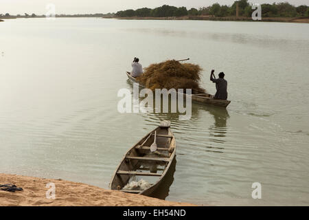 In der Nähe von NIAMEY, NIGER, 15. Mai 2012: Fährmänner Heuballen über den Fluss Niger tragen Stockfoto