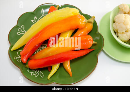 Eingelegte Paprika auf einer grünen Platte isoliert auf weiss Stockfoto