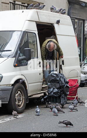 Ein älterer Mann füttert Tauben von der Rückseite eines Lieferwagens, Paris. Stockfoto