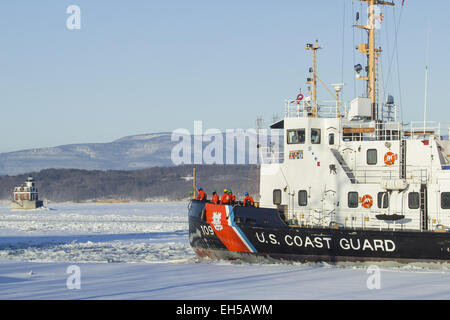 Hudson, New York, USA. 6. März 2015. Crew-Mitglieder von der United States Coast Guard Cutter "Sturgeon Bay" stehen an Deck, während der Eisbrecher eine Mole im Hudson River in Hudson, New York nähert. Der historische Hudson-Athen-Leuchtturm ist auf der linken Seite, und den Catskill Mountains sind im Hintergrund. © Tom Bushey/ZUMA Draht/Alamy Live-Nachrichten Stockfoto