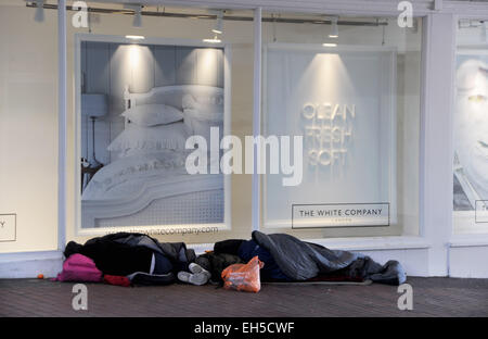 Brighton UK - zwei obdachlose, raue Schläfer haben sich für die Nacht vor dem Laden der White Company in Brighton vor ihrem Bettenfenster niedergelassen. Credit: Simon Dack/Alamy Live News Stockfoto