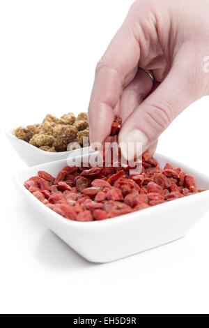 Frau Essen und essen Goji-Beere / Wolfsbeere und Maulbeere aus einer Schüssel auf weißem Hintergrund. Stockfoto