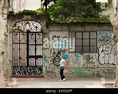 Argentinien, Buenos Aires, Almagro, Hipolito Yrigoyen, Grafiiti mit reich verzierten schmiedeeisernen Tor an Wand Stockfoto