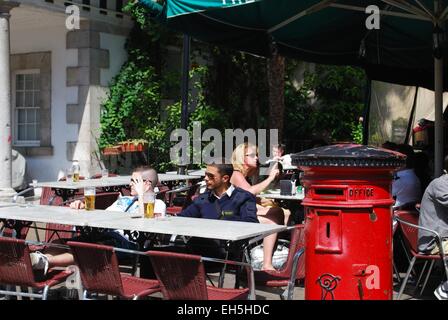Entspannende Touristen in einem Pub an der Main Street mit einem traditionellen britischen Briefkasten im Vordergrund, Gibraltar, Großbritannien. Stockfoto