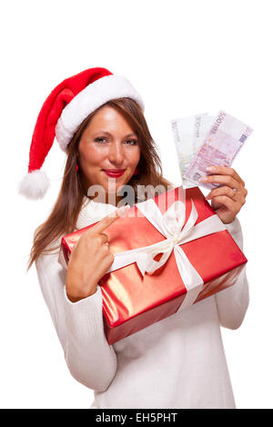 Temperamentvolle schöne junge Frau trägt eine Weihnachtsmütze mit einem großen roten Weihnachtsgeschenk und Geld, konzeptionelle erfolgreiche Xmas Sho Stockfoto