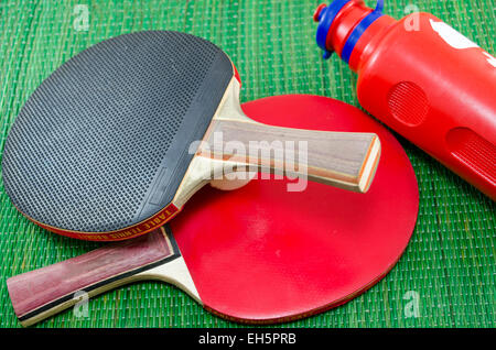 Zwei Vintage Tischtennisschläger und zwei Tischtennisbälle auf grünem Hintergrund Stockfoto