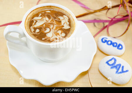 Weiße Tasse Kaffee mit dekorierten Schaum und Felsen sagen: "Guten Tag" Stockfoto