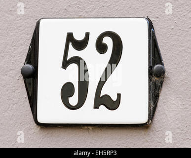 Zeichen der Hausnummer 52 in schwarzen Buchstaben auf eine graue Wand Stockfoto