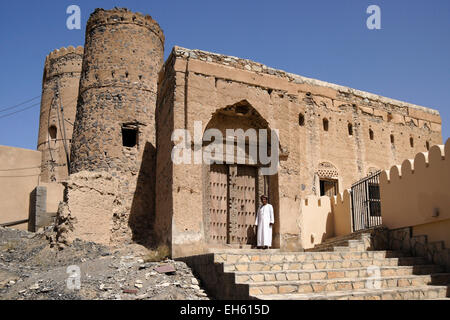 Mann in geschnitzte Holz Tür des alten Lehmziegeln bauen, Al-Mudayrib, Oman Stockfoto