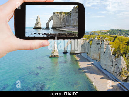 Konzept - Touristen nehmen Foto der englischen Kanalküste mit Klippen auf Etretat Cote d'albatre, Frankreich auf mobile Gadget zu reisen Stockfoto