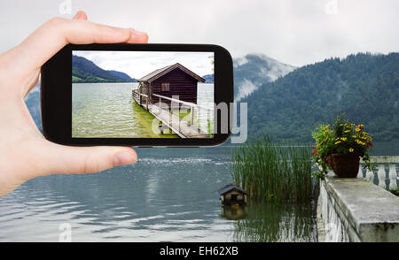 Reisen Sie Konzept - Touristen nehmen Foto von Schuppen auf See Schliersee in den Bayerischen Alpen auf mobile Gadget, Deutschland Stockfoto