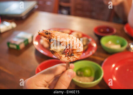 Eine Garnele auf einer Gabel über einem Tisch voller Essen Stockfoto