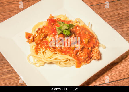 Spagett alla Bolognese und einige Koriander Blätter auf einem weißen Teller Stockfoto