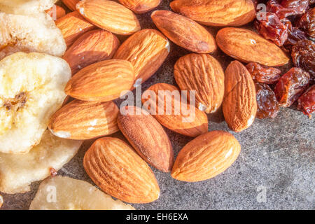 Leichte braune Mandeln, in der Nähe von trockenen Bananen- und Muttern auf einer Steinplatte Stockfoto