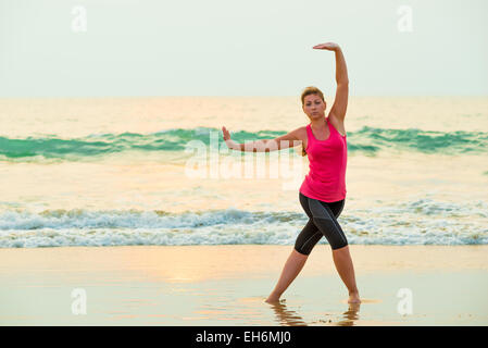 Aktive junge Frau, die Übungen auf einem Hintergrund des Meeres Stockfoto