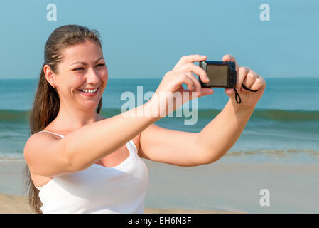 Junge charmante Frau mit einer Kamera in der Nähe des Meeres Stockfoto