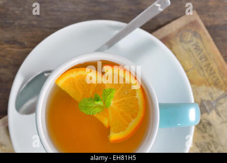 Tasse Tee und Orange Scheiben auf alten Holztisch Stockfoto