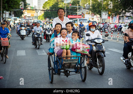 Schulkinder Reiten Fahrradrikscha auf einer belebten Straße, Ho-Chi-Minh-Stadt (Saigon), Vietnam, Indochina, Südostasien, Asien Stockfoto