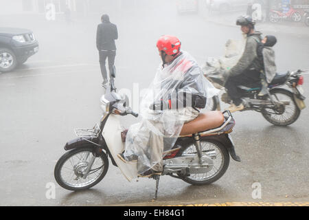 Scooter-Taxi-Fahrer raucht während er auf einen Tarif an einem nass und nebligen Tag im Stamm Hügelstadt von Sa Pa, Sapa, Vietnam wartet, Stockfoto