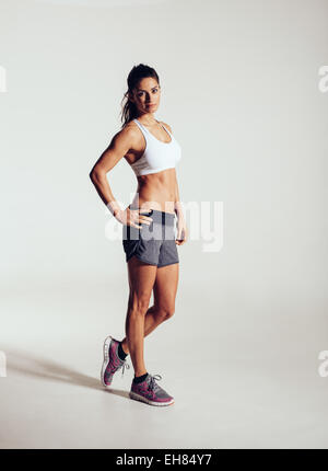 Voller Länge Aufnahme des jungen Fitness Model posiert im Studio. Gesunde junge Frau in Sportkleidung auf grauem Hintergrund stehen. Stockfoto