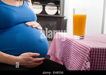 Frau in der Schwangerschaft volle Amtszeit in der Küche mit Orangensaft. Stockfoto