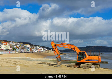 Nivellierung des Strands mit einem JCB Bagger, Lyme Regis, Dorset, England UK Stockfoto