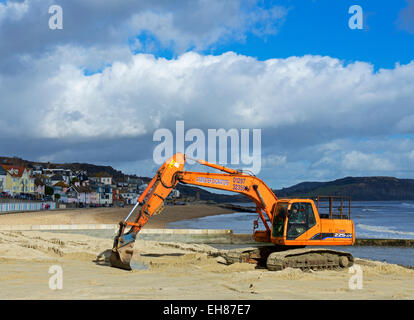 Nivellierung des Strands mit einem JCB Bagger, Lyme Regis, Dorset, England UK Stockfoto