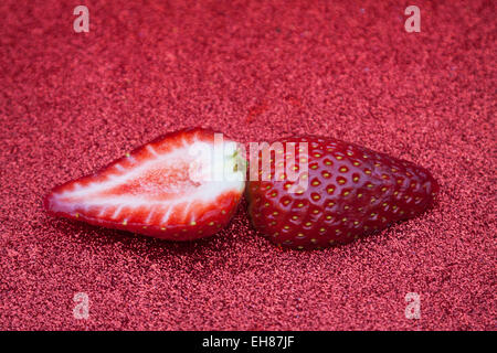 Eine Gruppe von Erdbeeren auf einem roten glitzernden Hintergrund. Stockfoto