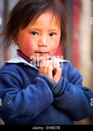 Ein junges Mädchen in Lo Manthang, Mustang, Nepal beginnt ein Hestitant "Namaste" Stockfoto