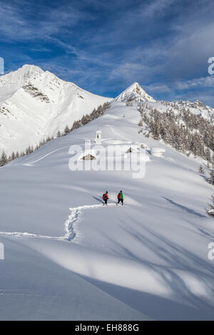 Wanderer, die versuchen, das kleine Dorf auf der Alm Scima Ansatz bedeckt in Schnee, Valchiavenna, Lombardei, Italien, Europa Stockfoto