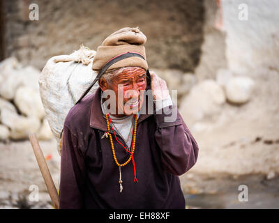 Älterer Mann tragen eine schwere Last durch Lo Manthang, Mustang, Nepal Stockfoto