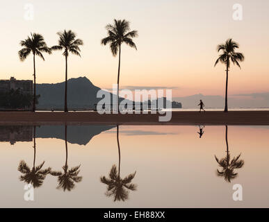 Strand von Waikiki, Oahu, Hawaii - Walker am Strand bei Sonnenaufgang mit Diamond Head hinter Stockfoto