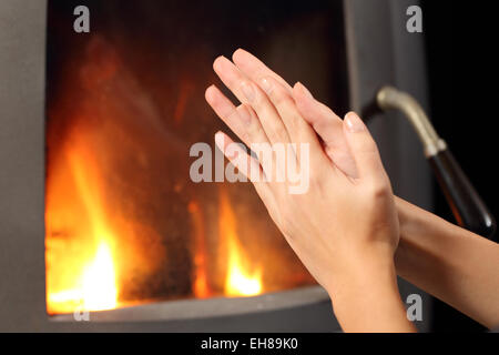 Frau, die Hände reiben und Heizung im Winter vor einen Kamin zu Hause Stockfoto