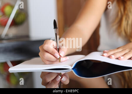 Nahaufnahme einer Frau Schreiber Hand schreiben in einem Notebook zu Hause in der Küche Stockfoto