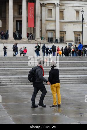 Touristen nehmen ein Selbstporträt mit einer Erweiterung kleben am Trafalgar Square in London. Stockfoto