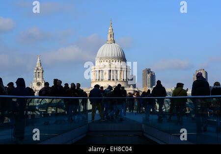 Menschen gehen über die Millennium Bridge, London, vom Schatten in die Sonne in Richtung St. Paul's Cathedral. Stockfoto